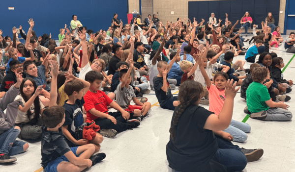 Students raising their hands during an assembly